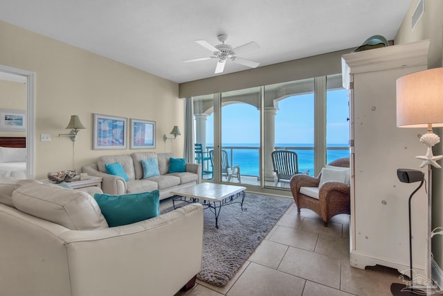 tiled living room with ceiling fan and a water view