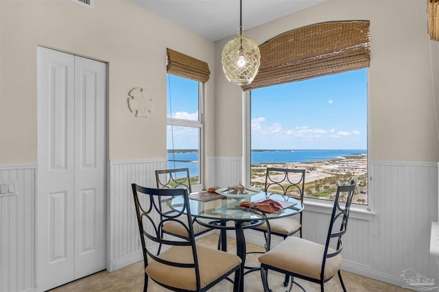 dining area featuring a water view, plenty of natural light, and light tile patterned floors