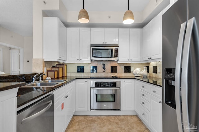 kitchen featuring appliances with stainless steel finishes, pendant lighting, sink, white cabinets, and dark stone counters