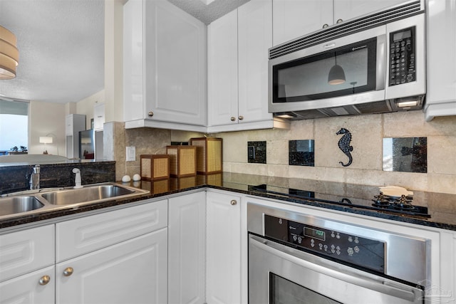 kitchen with sink, a textured ceiling, appliances with stainless steel finishes, white cabinets, and backsplash