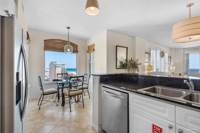 kitchen featuring sink, white cabinetry, dark stone countertops, pendant lighting, and stainless steel appliances