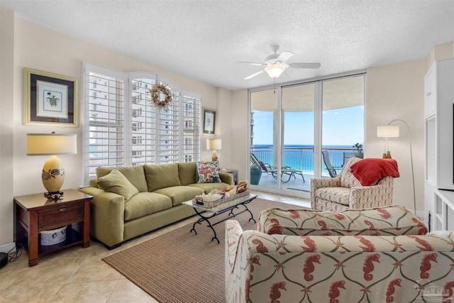 tiled living room with a water view, a textured ceiling, and ceiling fan