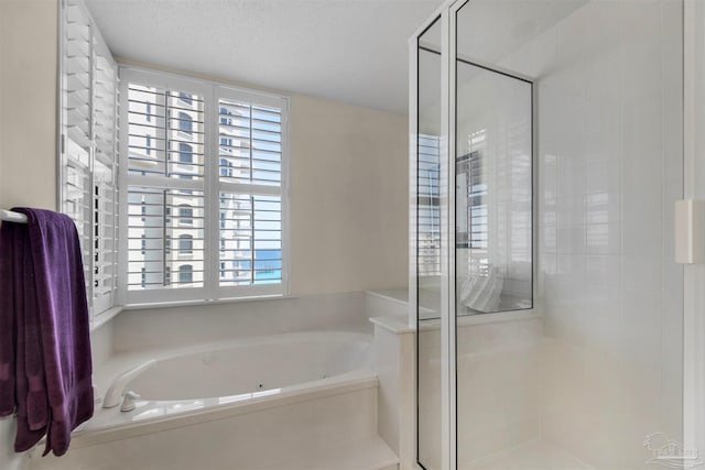 bathroom with a textured ceiling and separate shower and tub