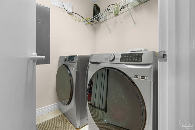 clothes washing area with tile patterned floors, electric panel, and washer and clothes dryer