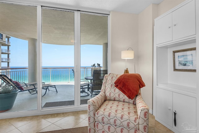 living area featuring a water view, a wall of windows, and light tile patterned floors