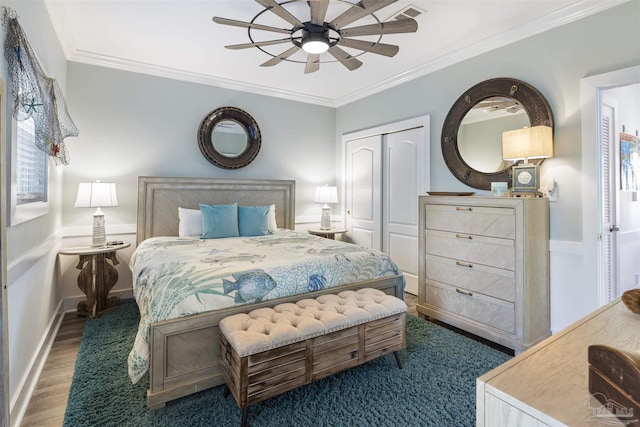 bedroom featuring a closet, visible vents, ornamental molding, wood finished floors, and baseboards