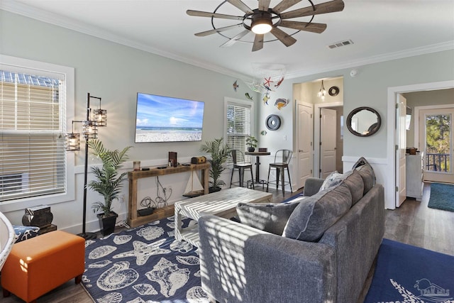 living area with ornamental molding, visible vents, plenty of natural light, and wood finished floors