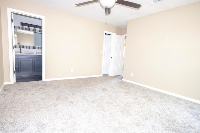 unfurnished bedroom featuring light carpet, ensuite bathroom, sink, and ceiling fan