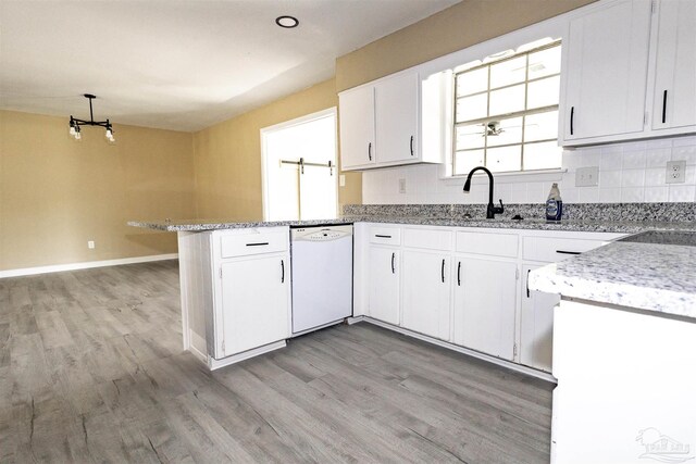 kitchen featuring white cabinets, dishwasher, light hardwood / wood-style floors, kitchen peninsula, and backsplash