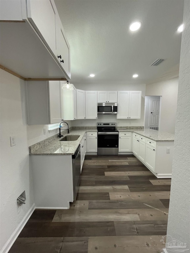 kitchen with a sink, light stone countertops, stainless steel appliances, white cabinetry, and visible vents