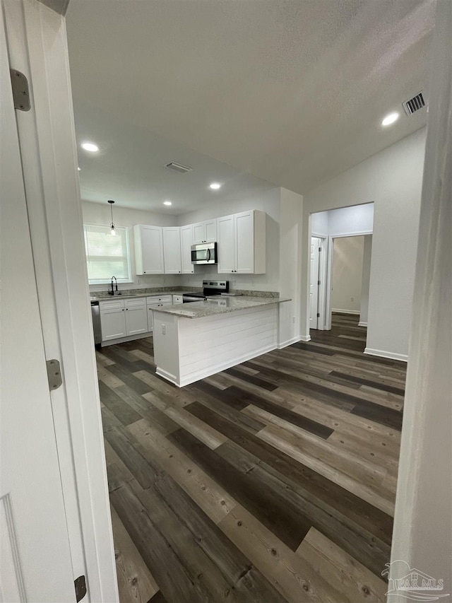 kitchen featuring a peninsula, stainless steel appliances, visible vents, white cabinetry, and light stone countertops