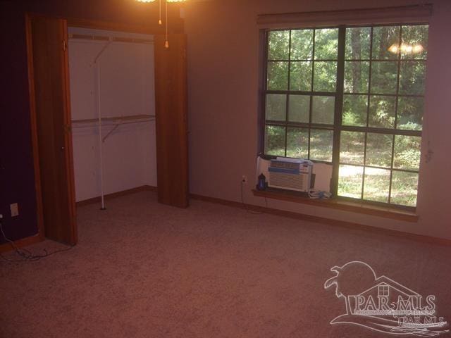 unfurnished bedroom featuring multiple windows, cooling unit, carpet floors, and a closet