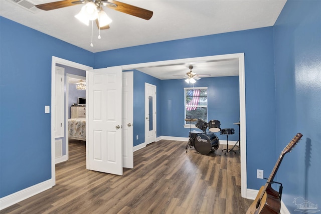 sitting room with a ceiling fan, visible vents, baseboards, and wood finished floors