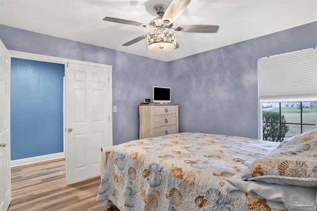 bedroom featuring ceiling fan, baseboards, and wood finished floors