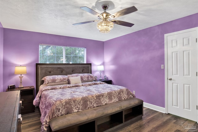 bedroom with a textured ceiling, ceiling fan, dark wood finished floors, and baseboards