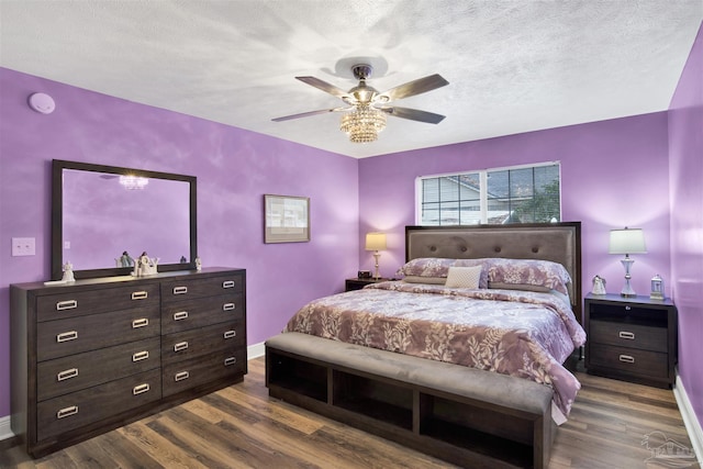 bedroom with dark wood-style floors, a textured ceiling, and baseboards