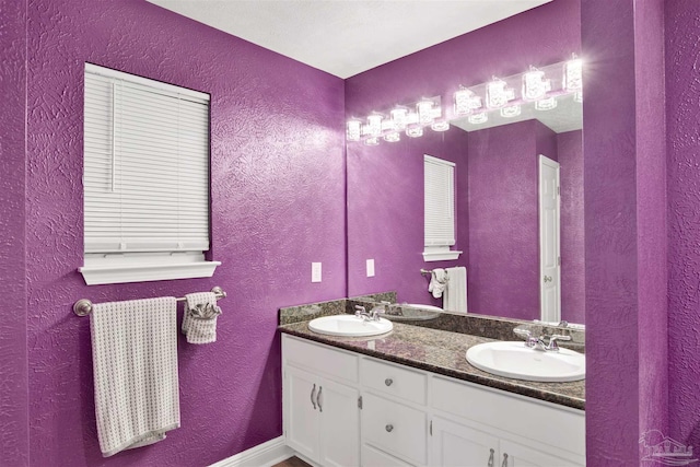 full bathroom with double vanity, a sink, and a textured wall