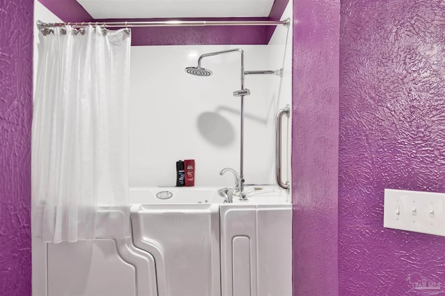 full bath featuring shower / tub combo with curtain and a textured wall