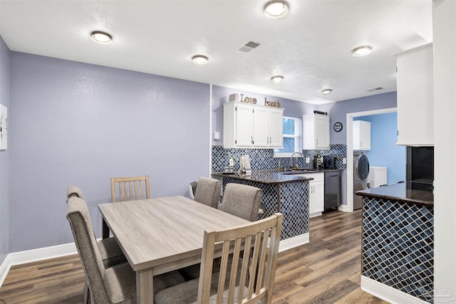 dining area with dark wood-style flooring, visible vents, baseboards, and separate washer and dryer