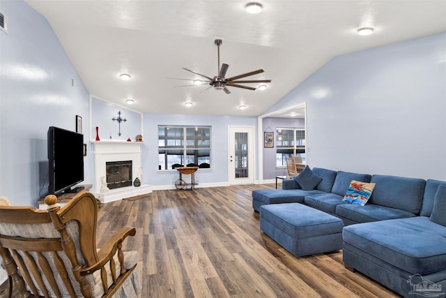 living room with a glass covered fireplace, visible vents, vaulted ceiling, and wood finished floors