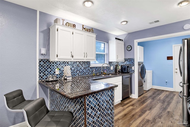 kitchen featuring a sink, visible vents, washer and dryer, black dishwasher, and freestanding refrigerator