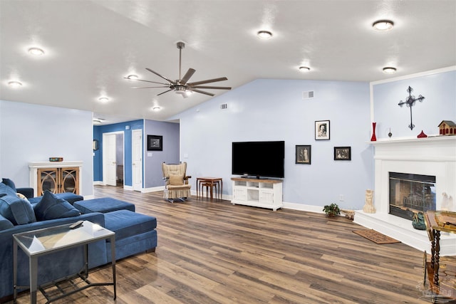 living area featuring lofted ceiling, visible vents, a glass covered fireplace, ceiling fan, and wood finished floors