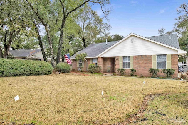 ranch-style home featuring brick siding, a front yard, and a shingled roof