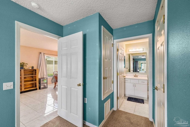 interior space featuring a textured ceiling, visible vents, tile patterned flooring, and vanity