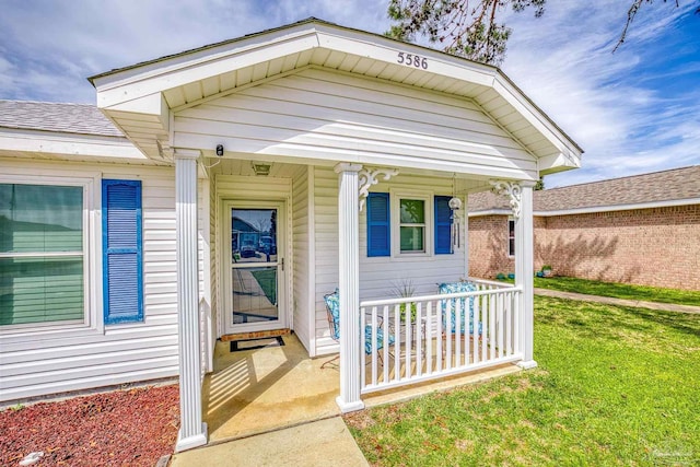 doorway to property with a porch and a yard