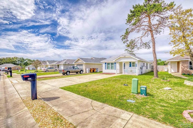 view of front of home with a porch, a residential view, driveway, and a front yard