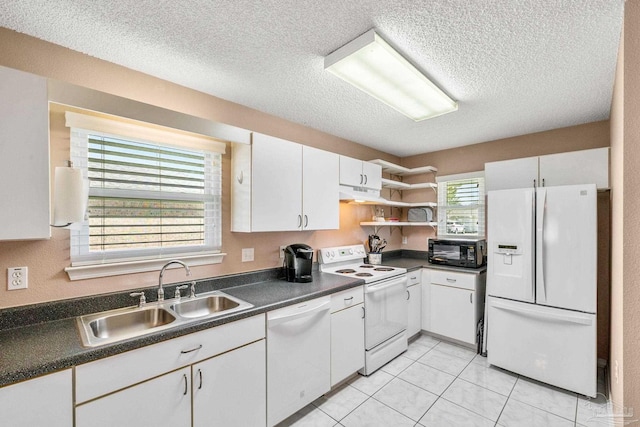 kitchen featuring dark countertops, white cabinets, a sink, white appliances, and under cabinet range hood