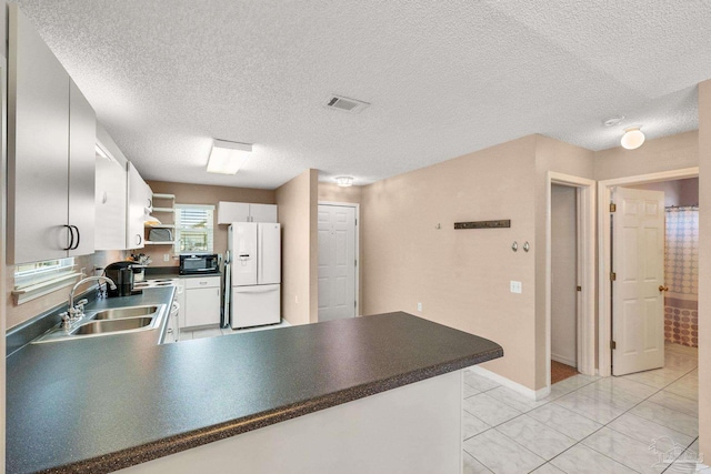 kitchen featuring dark countertops, black microwave, white fridge with ice dispenser, and white cabinetry