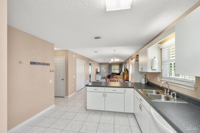 kitchen with dark countertops, visible vents, white cabinetry, a sink, and a peninsula