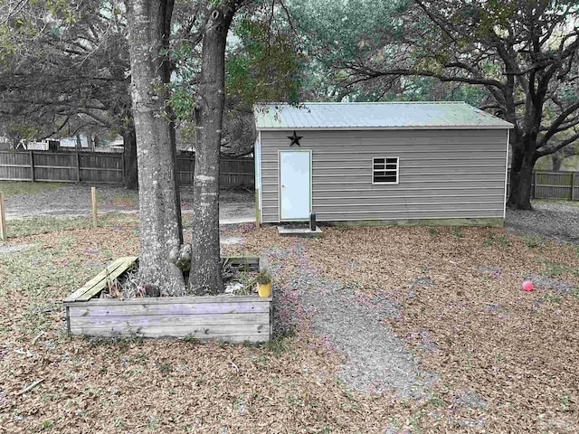 view of outdoor structure featuring a fenced backyard and an outbuilding