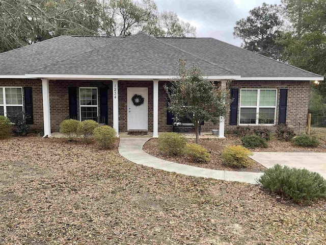 single story home featuring roof with shingles and brick siding