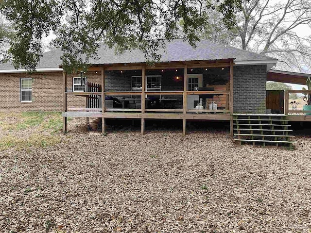 rear view of house featuring brick siding and a wooden deck