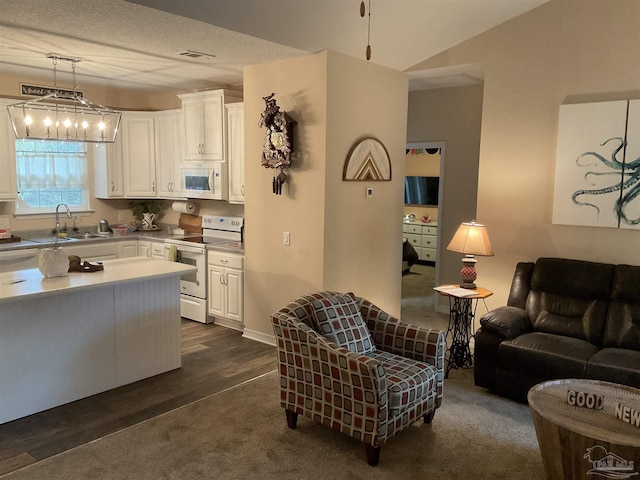 kitchen featuring white appliances, a sink, visible vents, white cabinetry, and pendant lighting