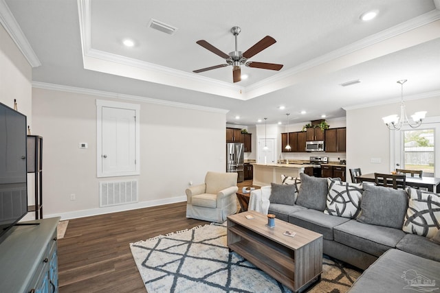 living room with baseboards, visible vents, a raised ceiling, ornamental molding, and dark wood-type flooring