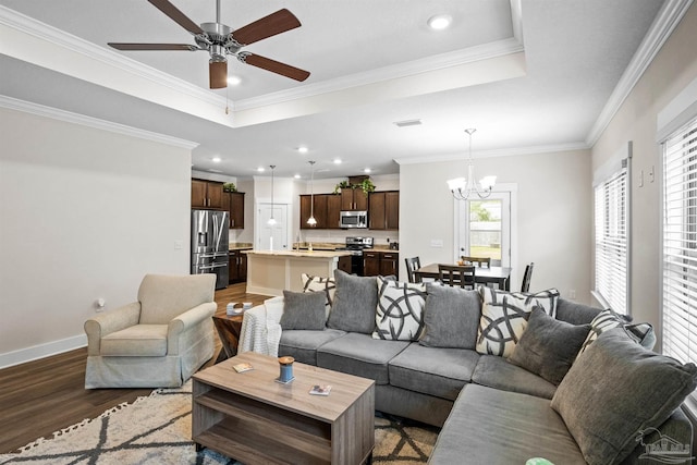 living area with a tray ceiling, crown molding, baseboards, and wood finished floors