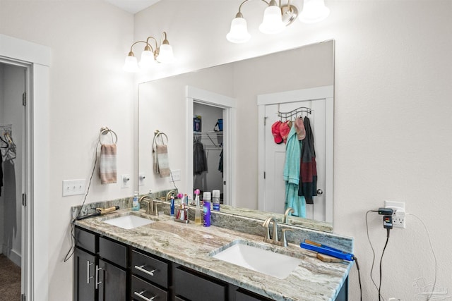 full bath with double vanity, a spacious closet, and a sink