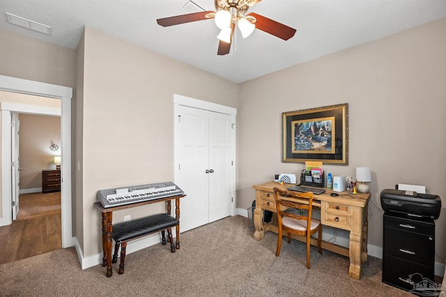 carpeted home office featuring ceiling fan, visible vents, and baseboards