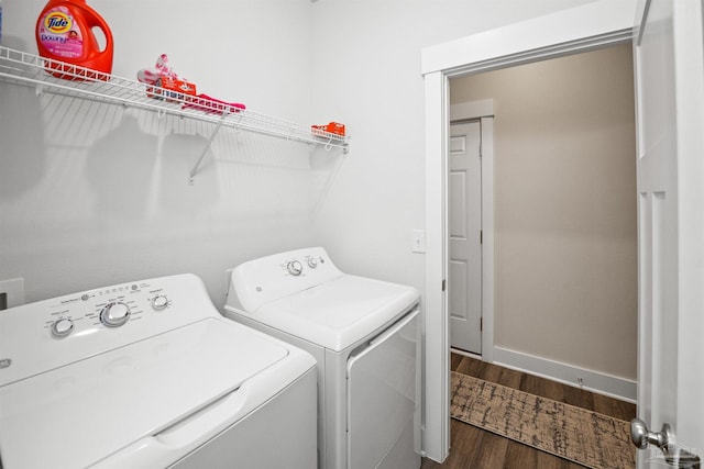 clothes washing area with dark wood-style floors, laundry area, washing machine and clothes dryer, and baseboards