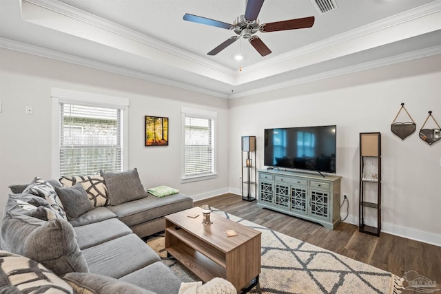 living room with a tray ceiling, wood finished floors, and baseboards