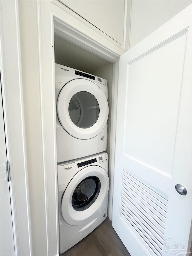 laundry room featuring stacked washer and dryer, laundry area, and dark wood-style flooring