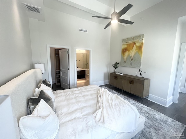 bedroom with baseboards, visible vents, a towering ceiling, dark wood-type flooring, and ensuite bathroom