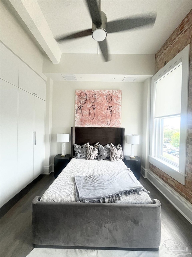 bedroom featuring baseboards, brick wall, ceiling fan, dark wood-style flooring, and a closet