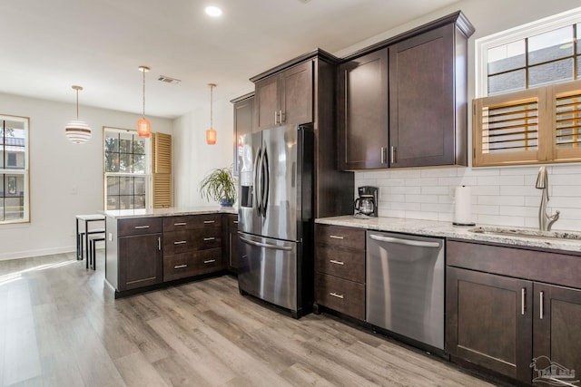 kitchen featuring pendant lighting, sink, light hardwood / wood-style flooring, dark brown cabinets, and stainless steel appliances