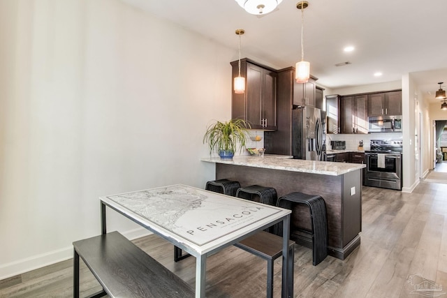 kitchen with dark brown cabinetry, light hardwood / wood-style flooring, kitchen peninsula, decorative light fixtures, and appliances with stainless steel finishes