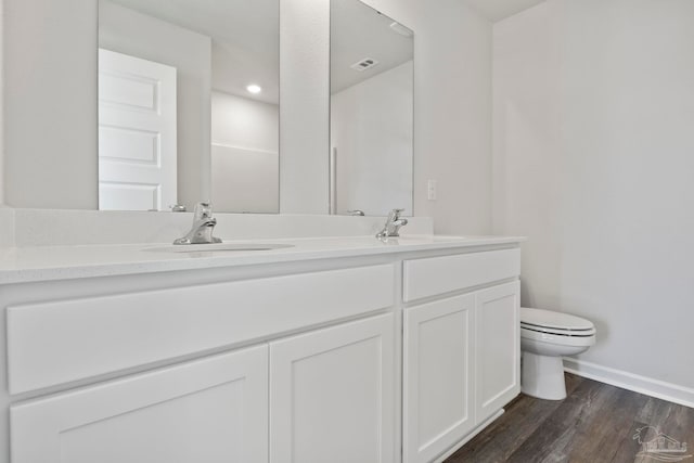 bathroom with toilet, wood finished floors, a sink, and baseboards