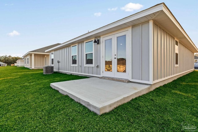 back of property featuring a patio, central air condition unit, french doors, board and batten siding, and a yard